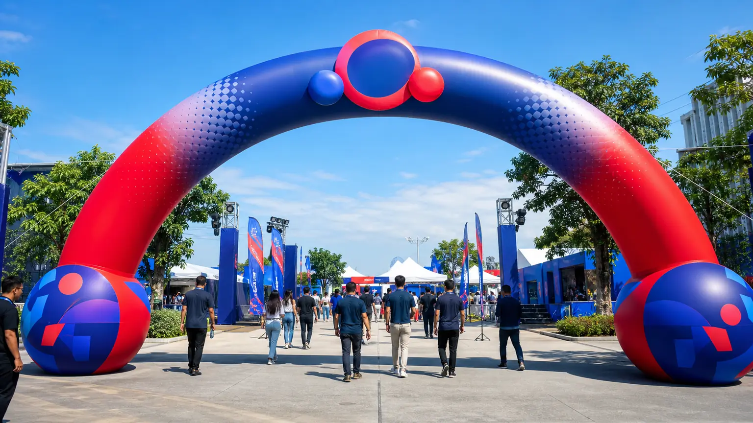 Red and blue inflatable branded entrance arch at an outdoor event with guests walking through