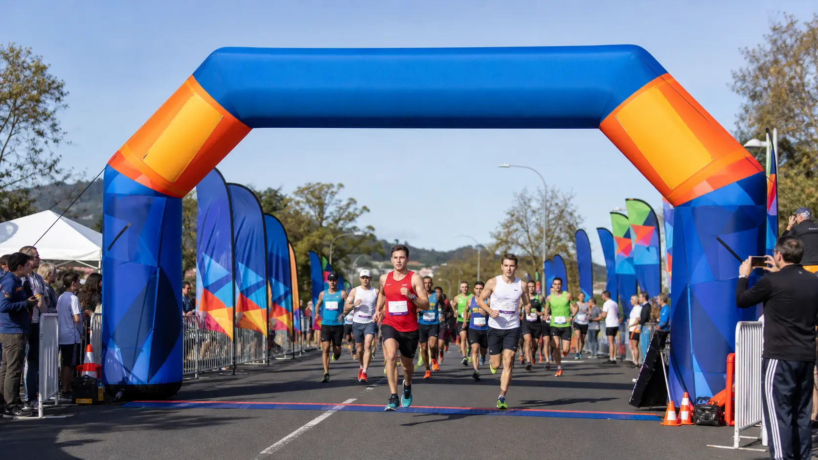 Blue and orange inflatable arch over runners at the start of a road race