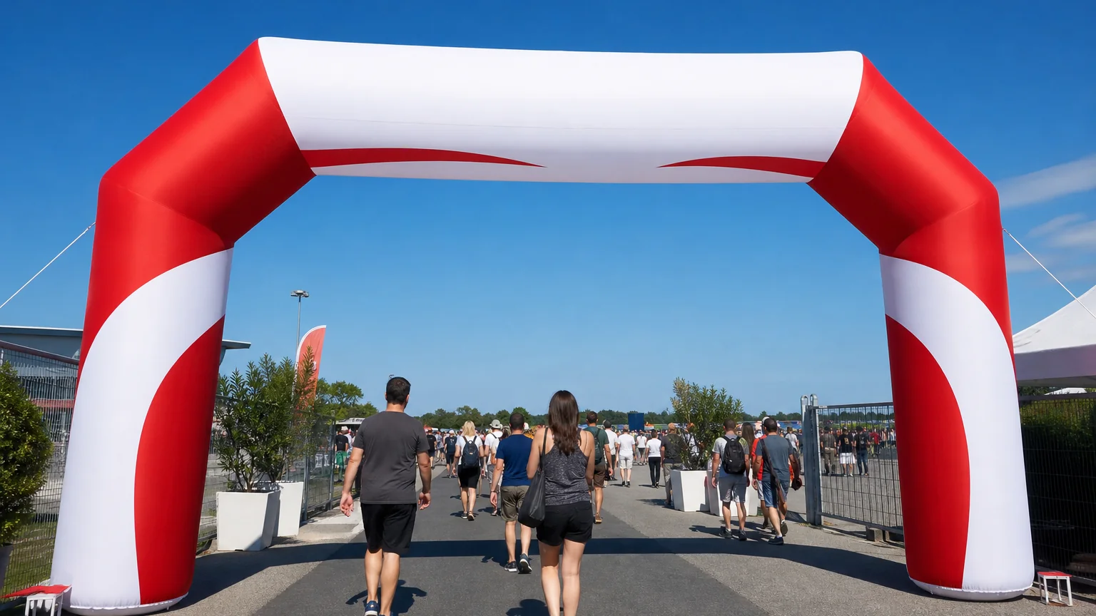 Red and white inflatable advertising arch spanning an event entrance with people walking through