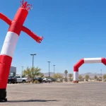 Werbe-Sky-Dancer und aufblasbarer Bogen auf einem trockenen, sonnenbeschienenen Parkplatz in einem heißen Klima