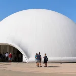 A large white inflatable dome tent in a public plaza with people gathered around the entrance